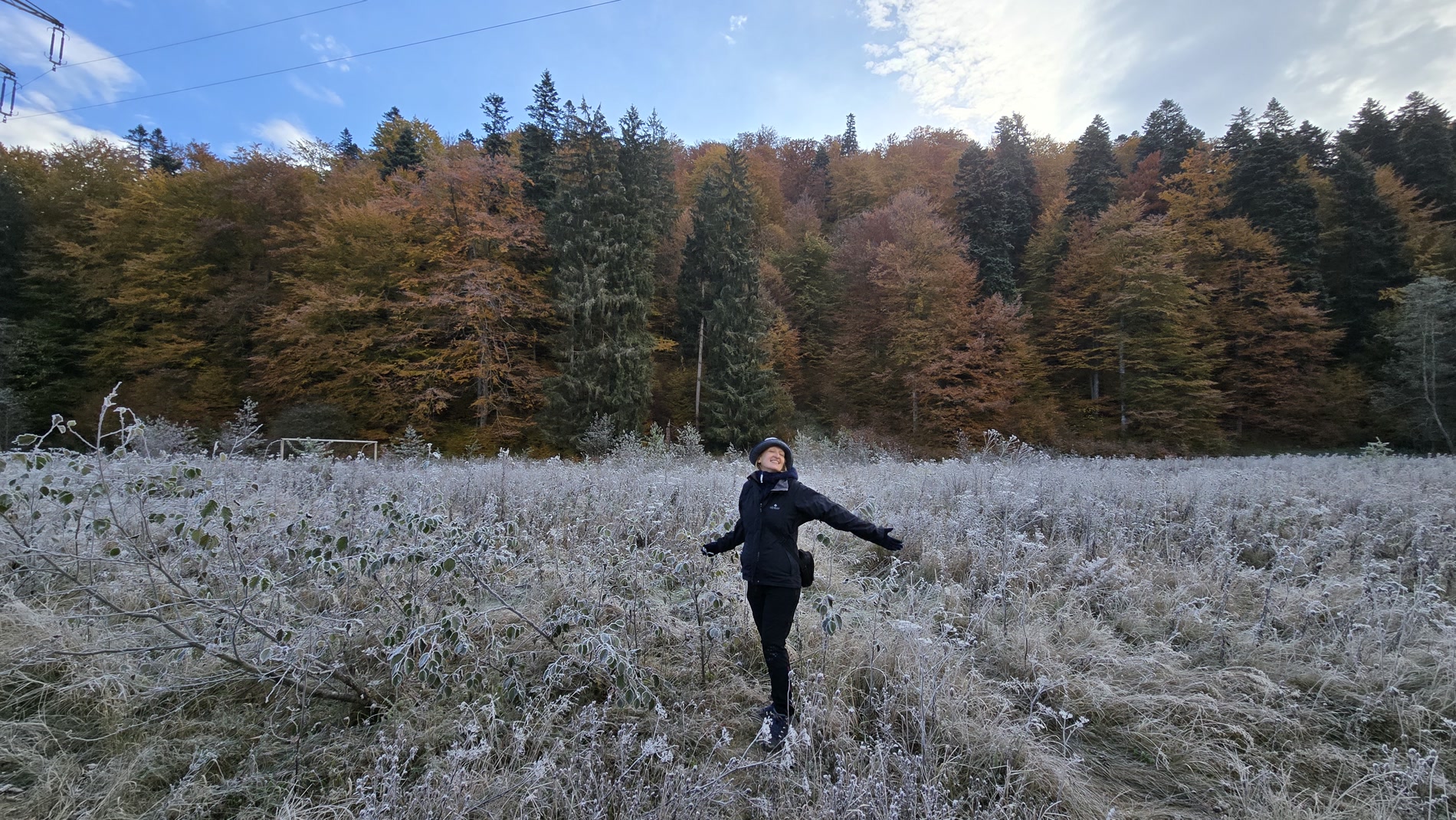 A participant opening her arms in an autumn landscape