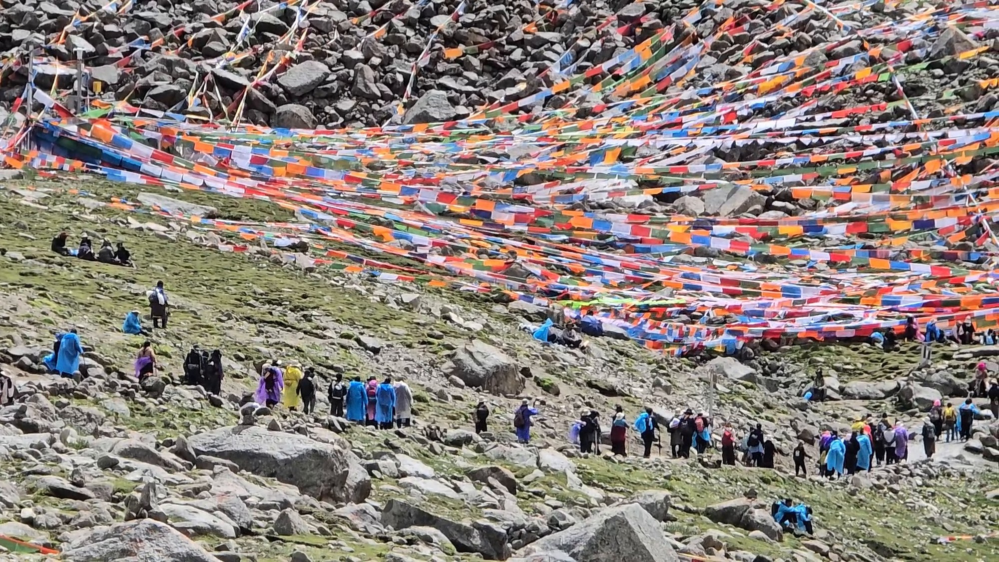 Pilgrims crossing the mountain beneath Tibetan prayer flags